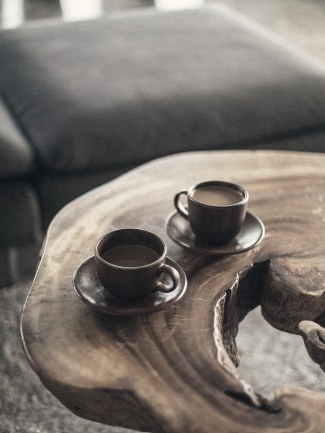 Two ceramic cups of coffee on a live-edge wooden table